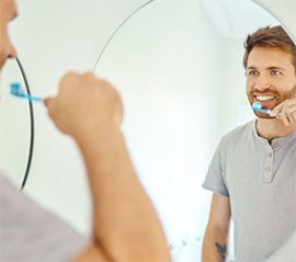 Man brushing his teeth in front of bathroom mirror