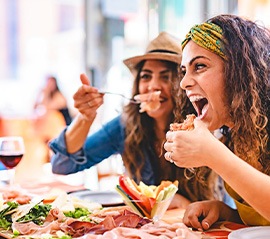 Friends smiling while enjoying meal in restaurant