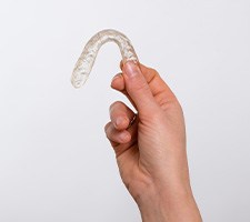 Hand holding oral appliance for sleep apnea against neutral background