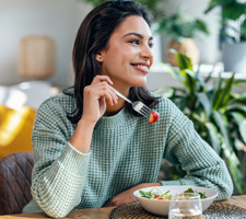 Woman smiling while eating healthy meal at home