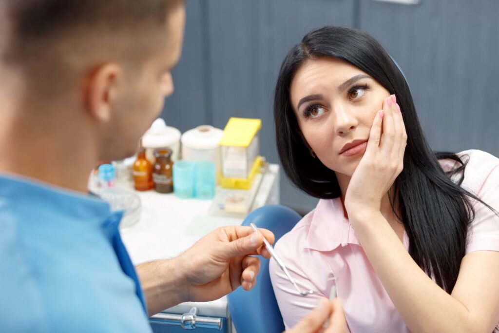 A woman holding her jaw in pain at the dentist's office.